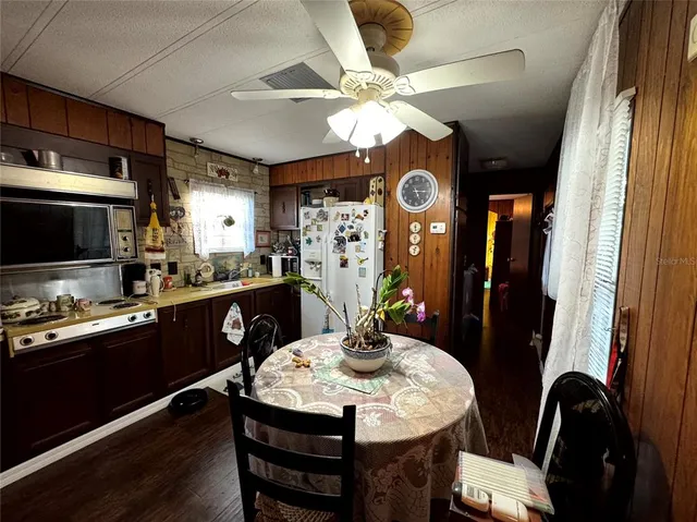 a kitchen with stainless steel appliances kitchen island granite countertop a stove a refrigerator a microwave a dining table and chairs with wooden floor