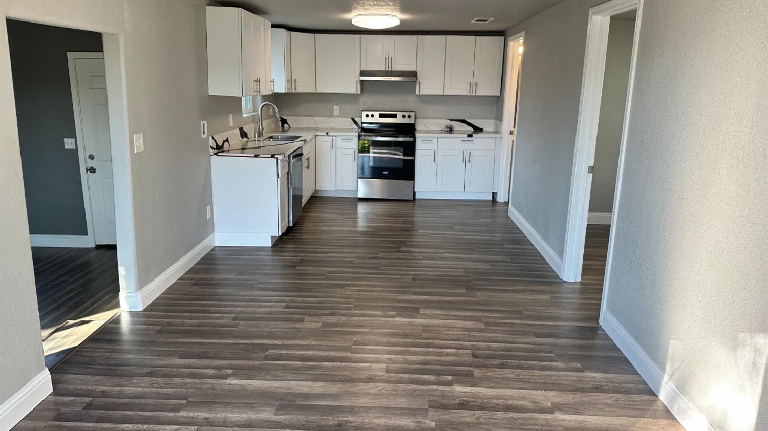 749 East Pleasant Street Coalinga, CA 93210 - Photo 3 of 16 a kitchen with granite countertop wooden floors stainless steel appliances and sink