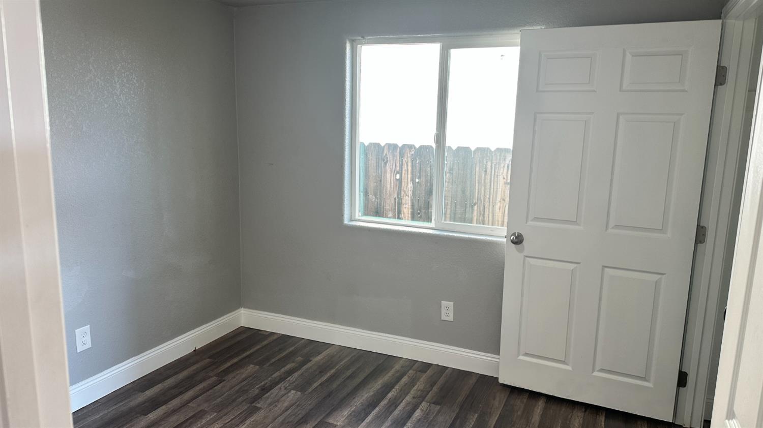 749 East Pleasant Street Coalinga, CA 93210 - Photo 8 of 16 a view of an empty room with wooden floor and a window