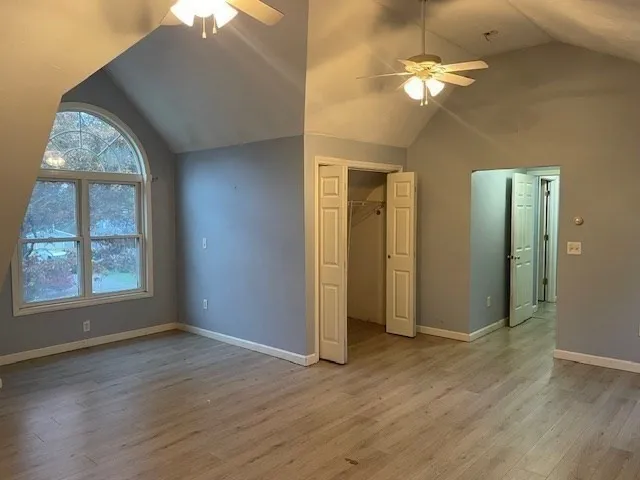 an empty room with wooden floor and a chandelier fan