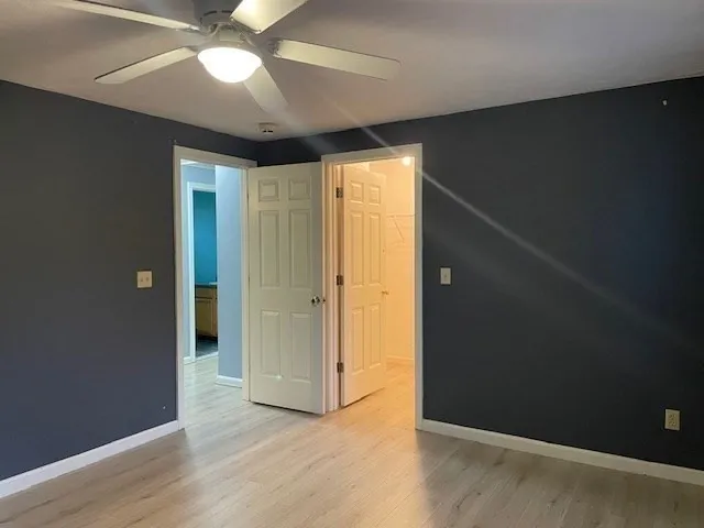 an empty room with wooden floor closet and windows