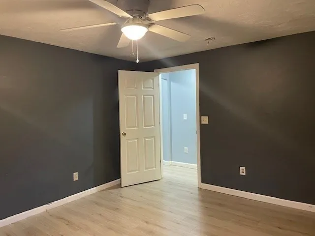 an empty room with wooden floor fan and window