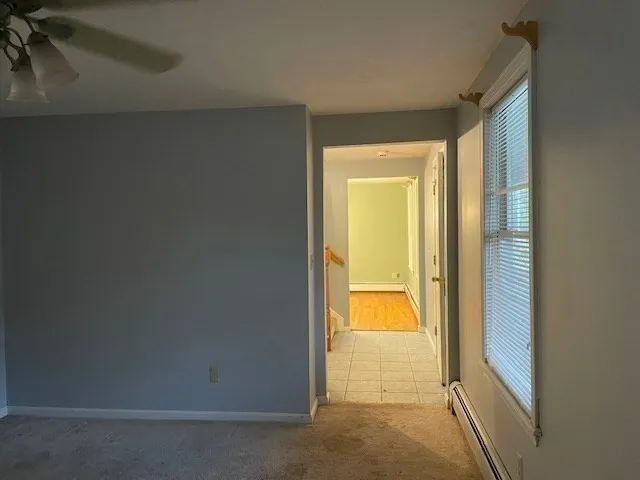 an empty room with chandelier fan and windows