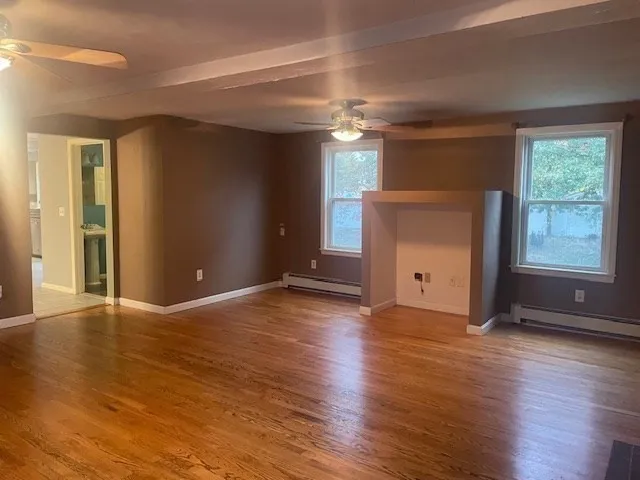 a view of empty room with wooden floor and fan