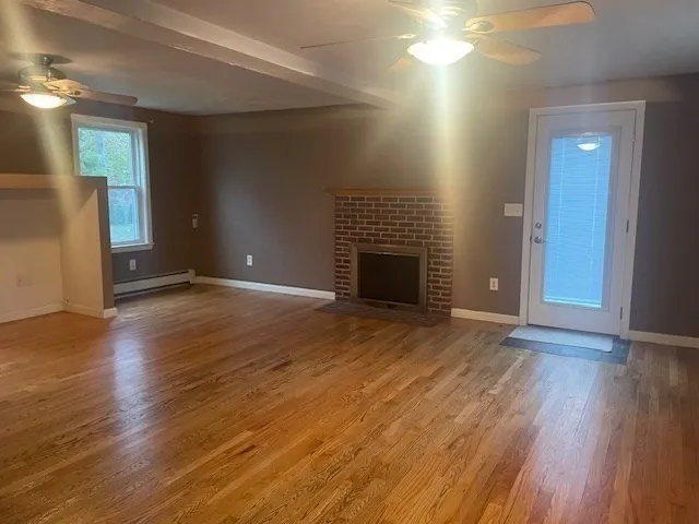 a view of an empty room with wooden floor and a fireplace