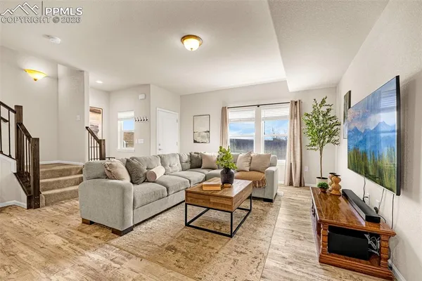 a living room with furniture a flat screen tv and a floor to ceiling window