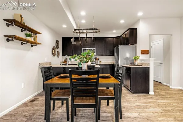 a kitchen with stainless steel appliances kitchen island granite countertop a table chairs refrigerator and microwave