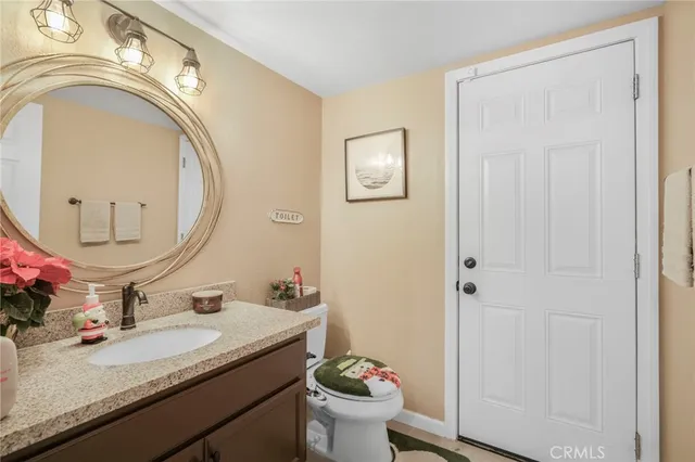 a bathroom with a granite countertop toilet a sink and a mirror