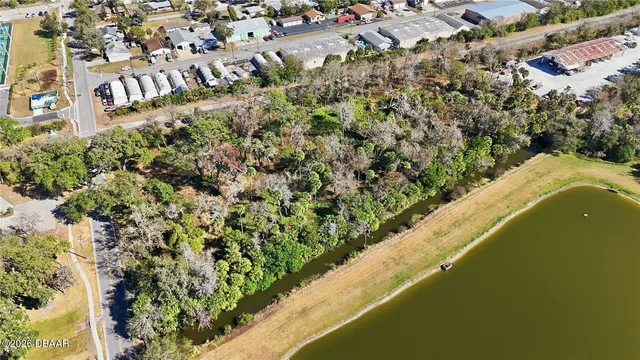 an aerial view of a residential houses with outdoor space and trees