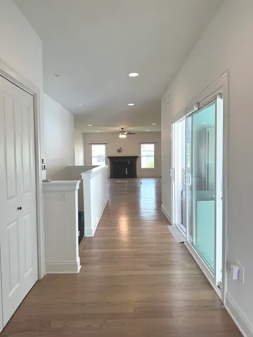a view of a hallway with wooden floor and a kitchen