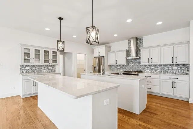 a large kitchen with kitchen island a stove a sink a center island and wooden floor