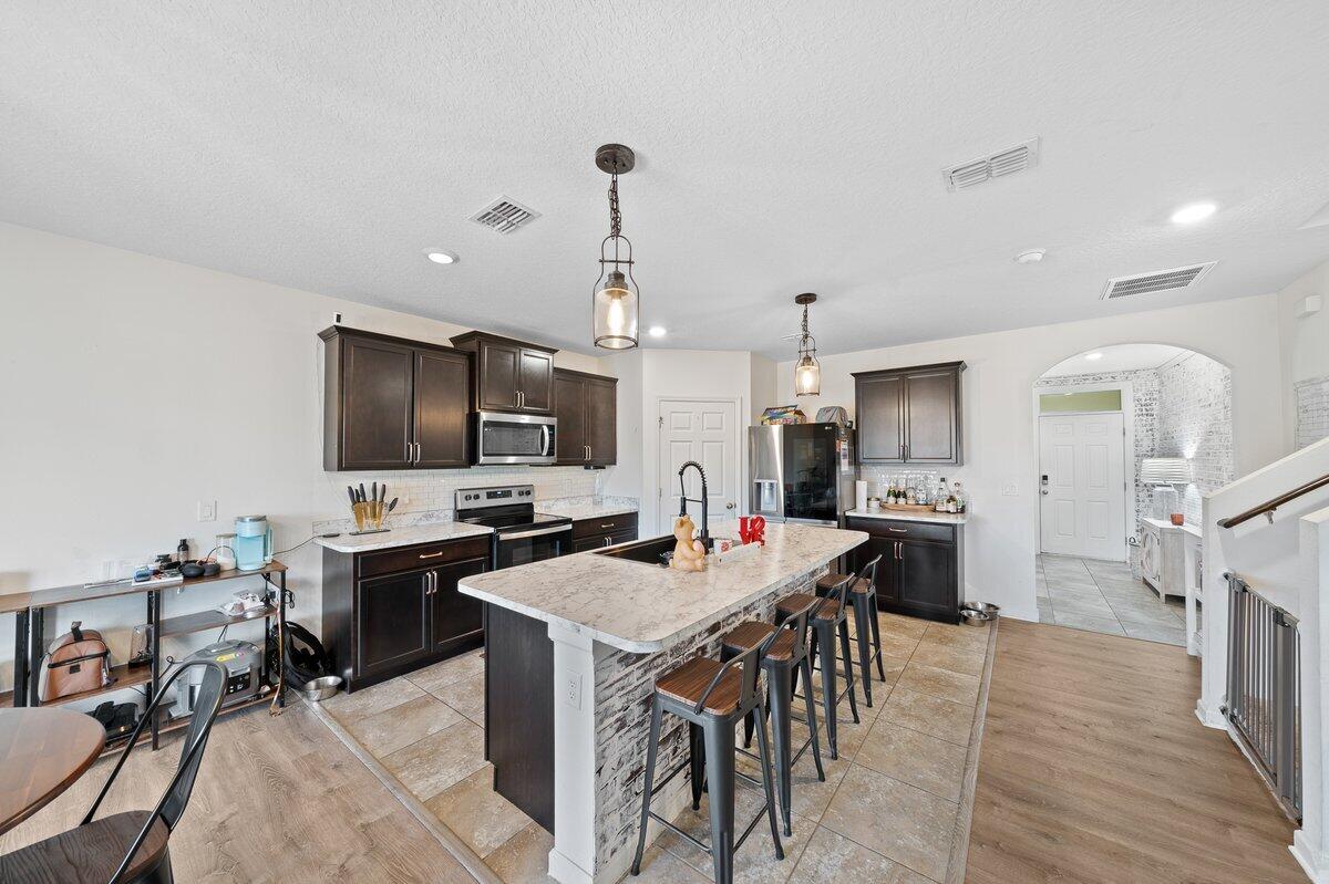 1652 Saxton Road Cocoa, FL 32926 - Photo 7 of 30 a kitchen with stainless steel appliances a stove a sink dishwasher a oven with a dining table and chairs