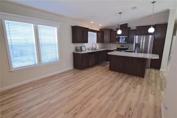 a large kitchen with a large counter top a sink stainless steel appliances and cabinets