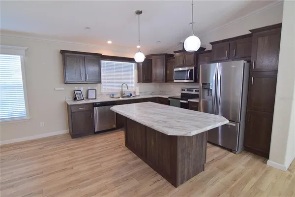 a kitchen with stainless steel appliances granite countertop a sink a stove a refrigerator and island with wooden floor