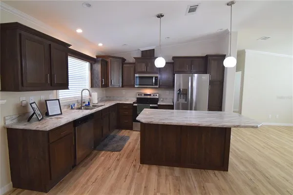 a kitchen with stainless steel appliances granite countertop wooden floors wooden cabinets a sink and a stove