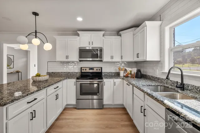 a large kitchen with stainless steel appliances granite countertop a sink a stove and dishwasher with wooden cabinets