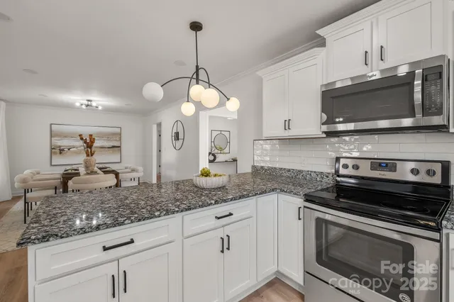 a kitchen with granite countertop a sink stainless steel appliances and white cabinets