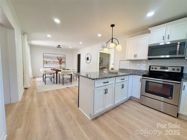 a kitchen with granite countertop a stove top oven a sink dishwasher a dining table and chairs with wooden floor