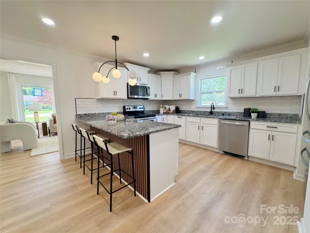 a kitchen with kitchen island granite countertop wooden floors and white cabinets