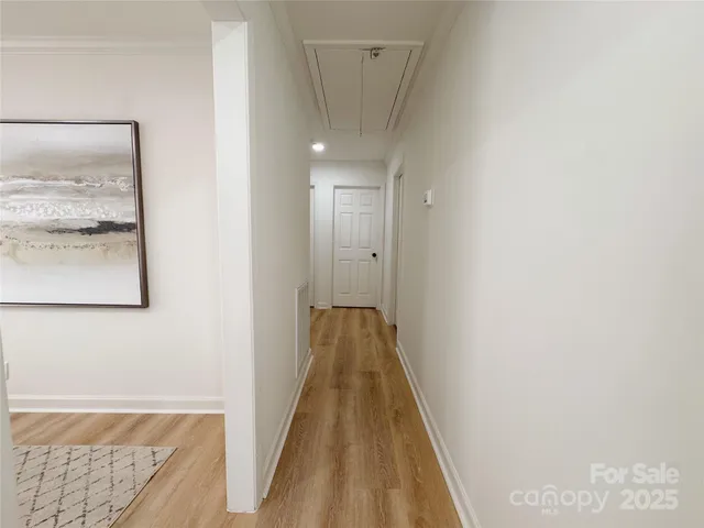 a view of a hallway with wooden floor and a bathroom