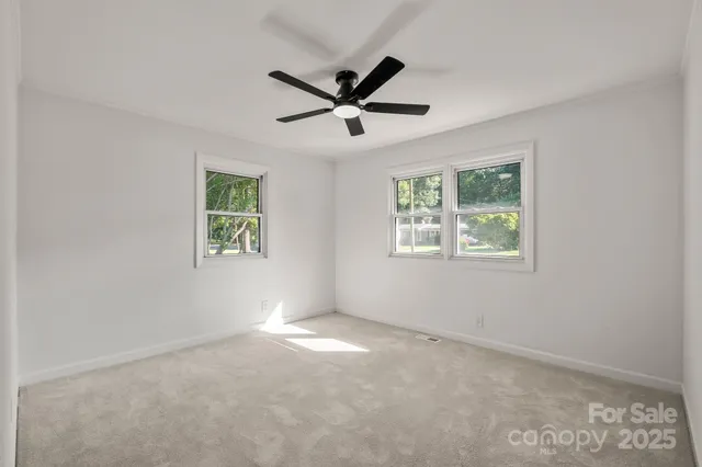 an empty room with windows and ceiling fan