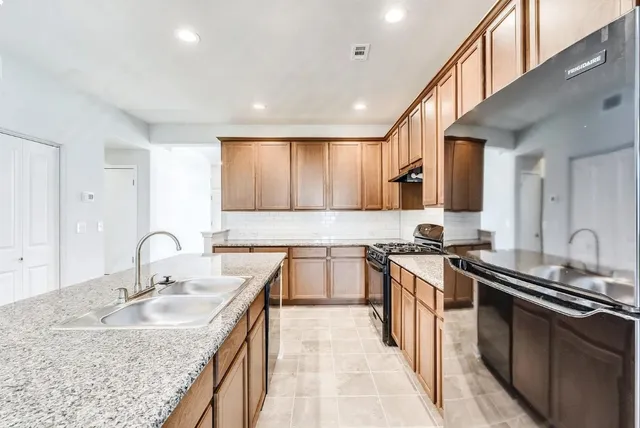 a kitchen with granite countertop a sink stove and cabinets