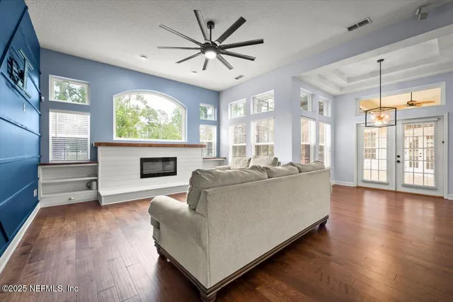 a living room with furniture large window and wooden floor