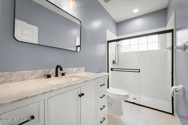 a bathroom with a granite countertop sink a toilet and a mirror