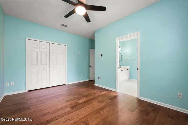 an empty room with wooden floor and a ceiling fan