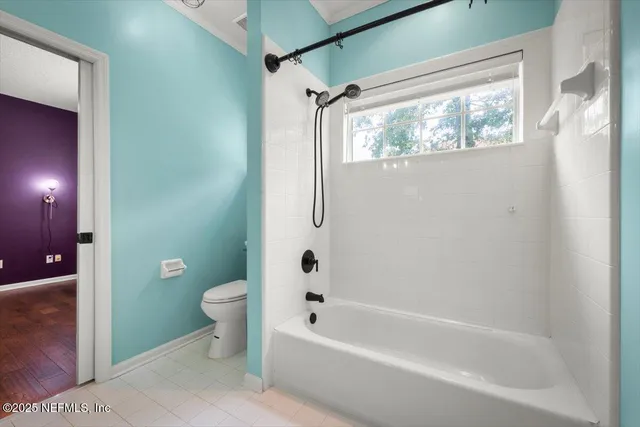 a bathroom with a bathtub toilet and window