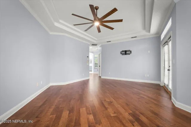 an empty room with wooden floor and ceiling fan