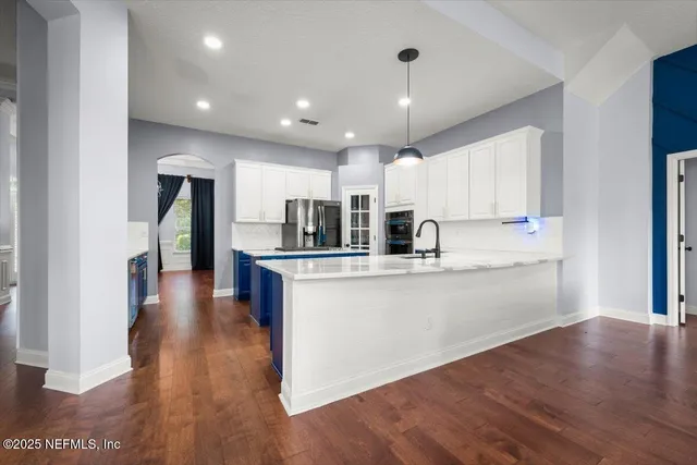 a kitchen with stainless steel appliances granite countertop a refrigerator a sink dishwasher and a oven with wooden floor