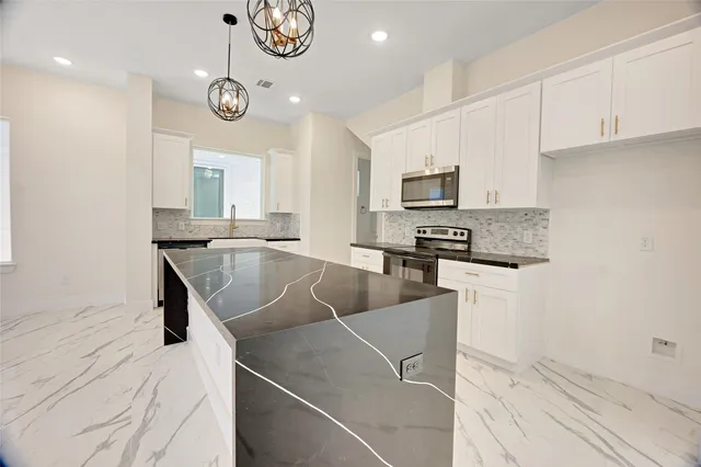 a kitchen with stainless steel appliances granite countertop a sink a stove top oven a chimney and a counter top space