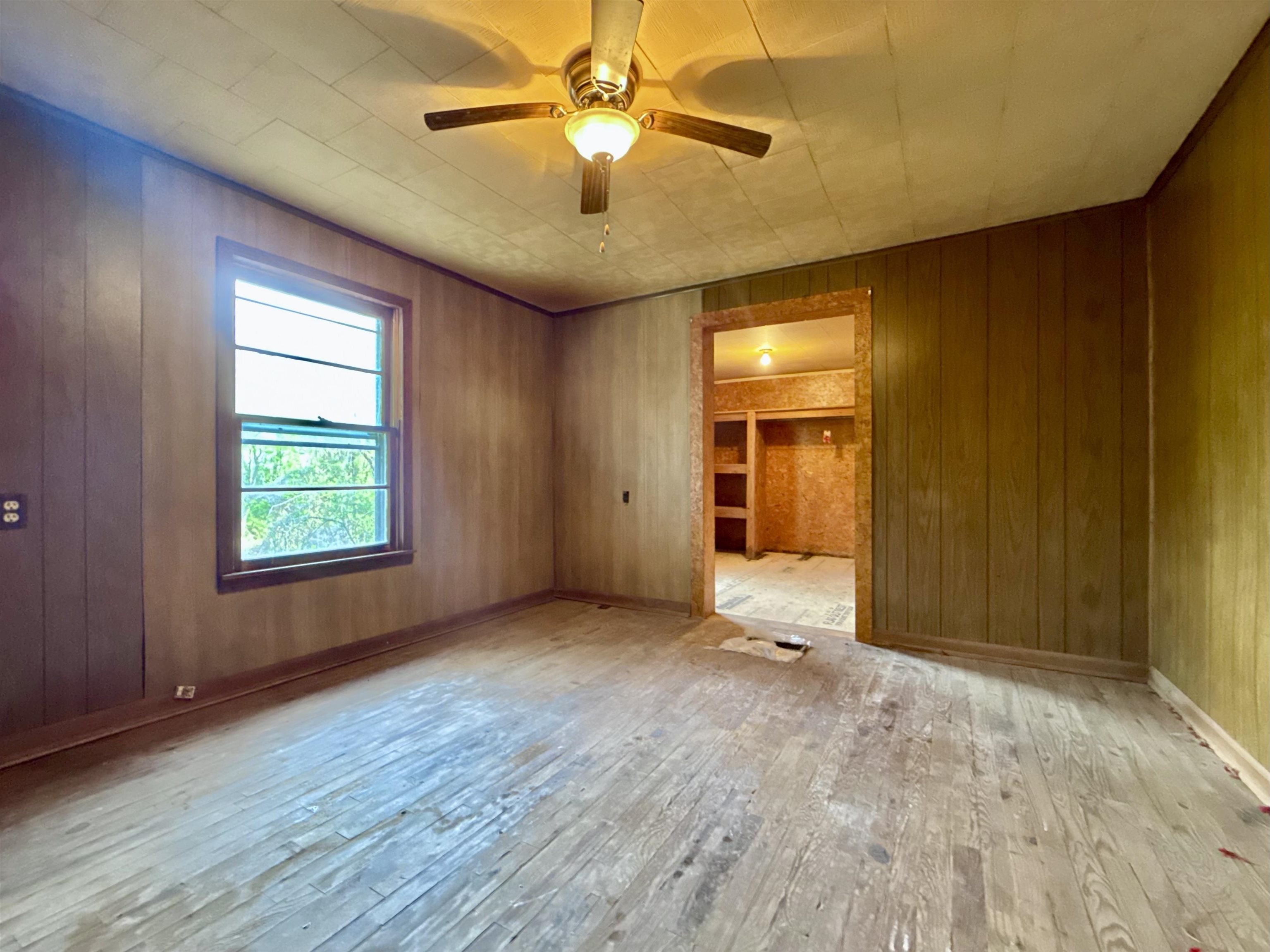 845 Needham Road Drummonds, TN 38023 - Photo 15 of 22 Empty room with wooden walls, hardwood / wood-style floors, and a ceiling fan