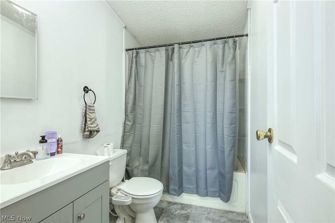 7848 Clay Pike Road Cambridge, OH 43725 - Photo 10 of 12 Full bathroom with toilet, oversized vanity, a textured ceiling, tile flooring, and shower / tub combo