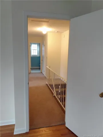 a view of a hallway with wooden floor and staircase