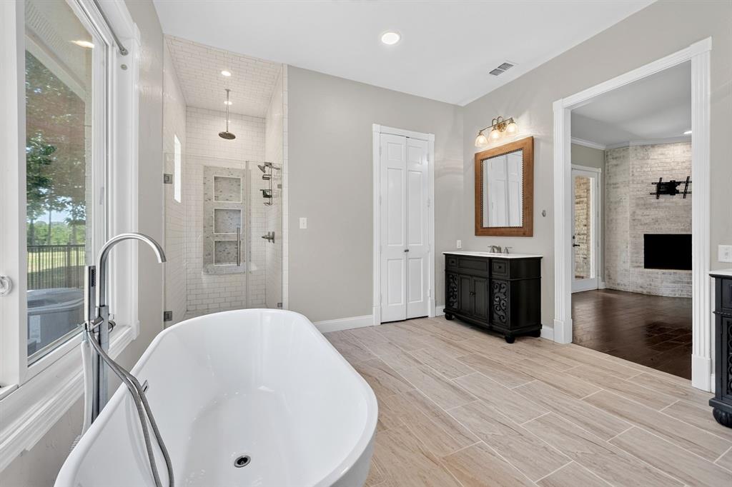1201 Robbins Road Athens, TX 75751 - Photo 23 of 40 Experience luxury living in this beautifully designed primary bathroom, featuring a captivating view of a brick wood-burning fireplace from the primary bedroom. This exquisite space combines comfort and elegance, transforming everyday moments into a relaxing retreat.