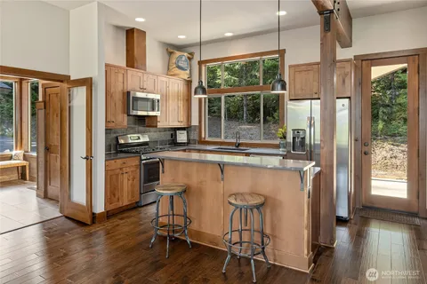 a kitchen with stainless steel appliances granite countertop a table chairs refrigerator and sink