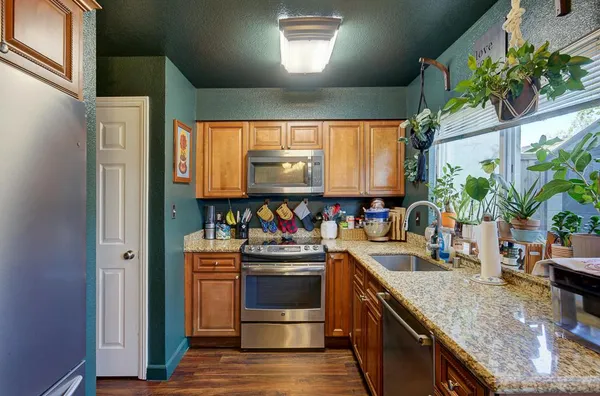 a kitchen with stainless steel appliances granite countertop a sink a stove and a wooden floors