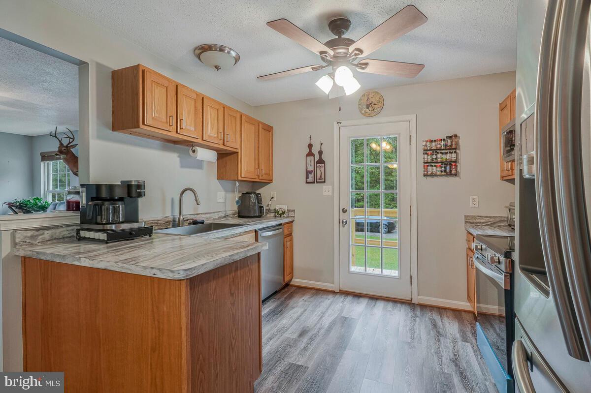 6115 Port Tobacco Road La Plata, MD 20646 - Photo 4 of 27 a kitchen with stainless steel appliances granite countertop a sink a stove a refrigerator wooden floor and a dining table