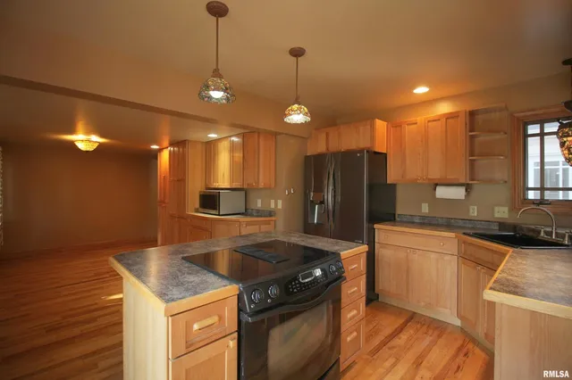 a kitchen with granite countertop a stove a sink a refrigerator and wooden floor