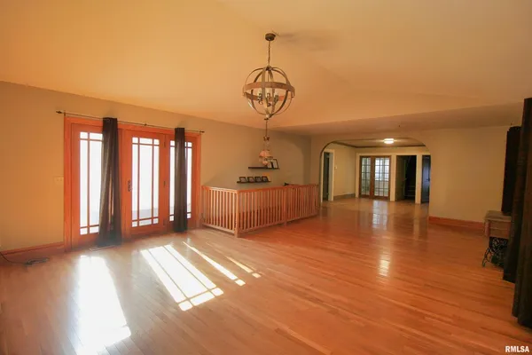 a view of a room with wooden floor chandeliers and kitchen view