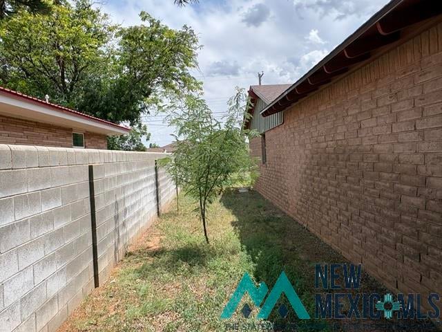 1037 Oakhurst Road Clovis, NM 88101 - Photo 2 of 21 Exterior brick wall with a shingle roofline, complemented by a concrete block fence