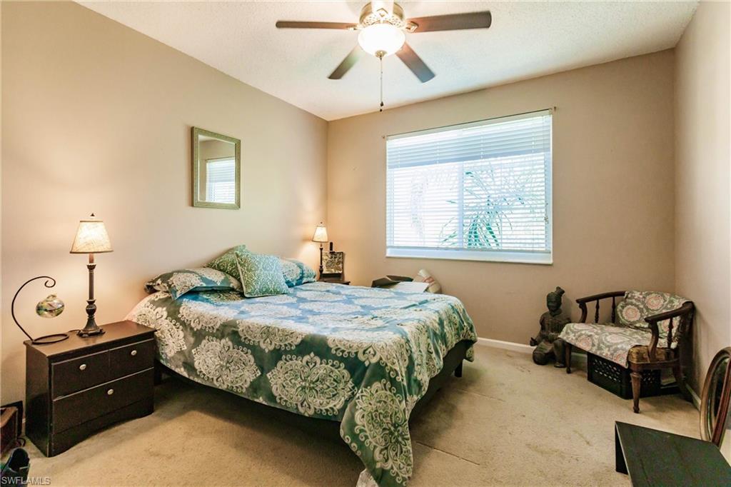 1230 Reserve Way, Unit 302 Naples, FL 34105 - Photo 13 of 28 a bedroom with a bed and a chandelier