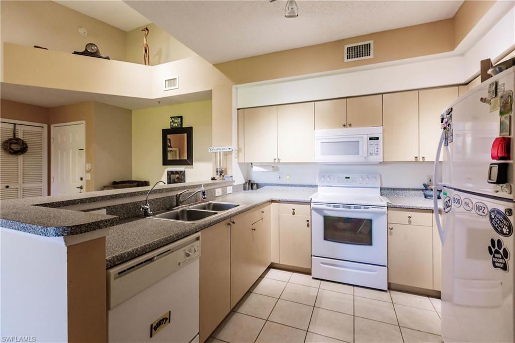 1230 Reserve Way, Unit 302 Naples, FL 34105 - Photo 9 of 28 a kitchen with a sink stove and cabinets