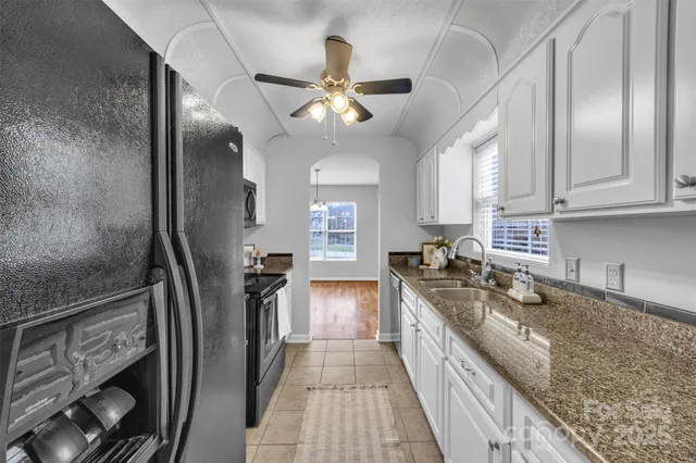 a kitchen with granite countertop a sink a stove and wooden cabinets