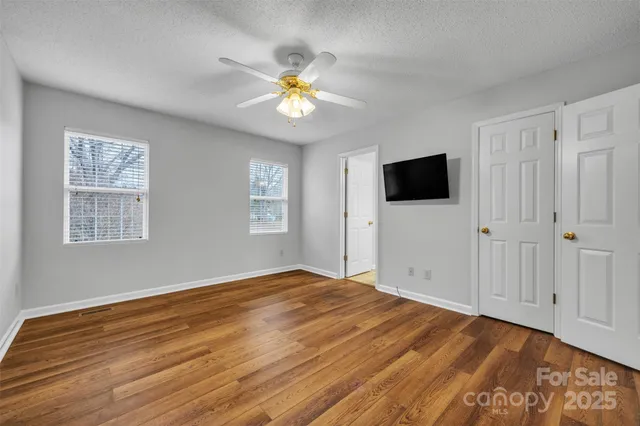 a view of empty room with wooden floor and fan