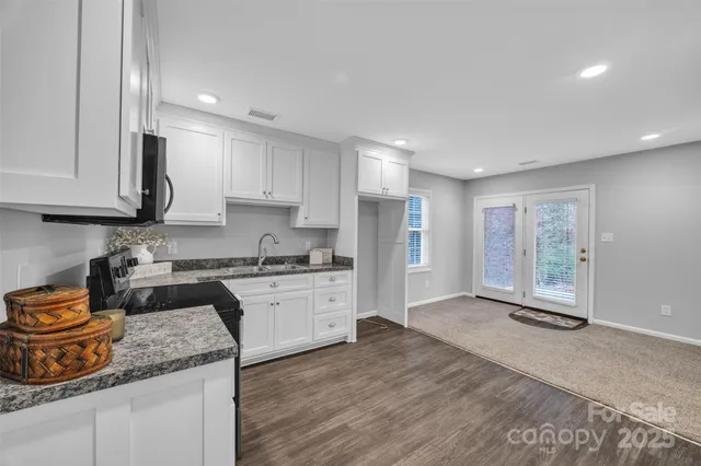a kitchen with stainless steel appliances granite countertop a stove a sink and a microwave