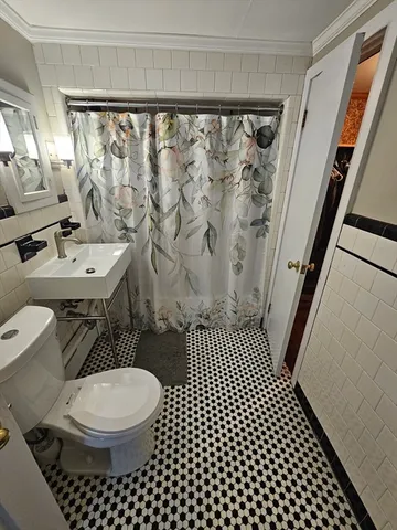 a bathroom with a sink a toilet a shower curtain and a mirror