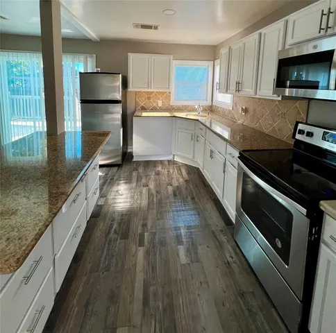 a kitchen with kitchen island granite countertop a sink appliances and cabinets